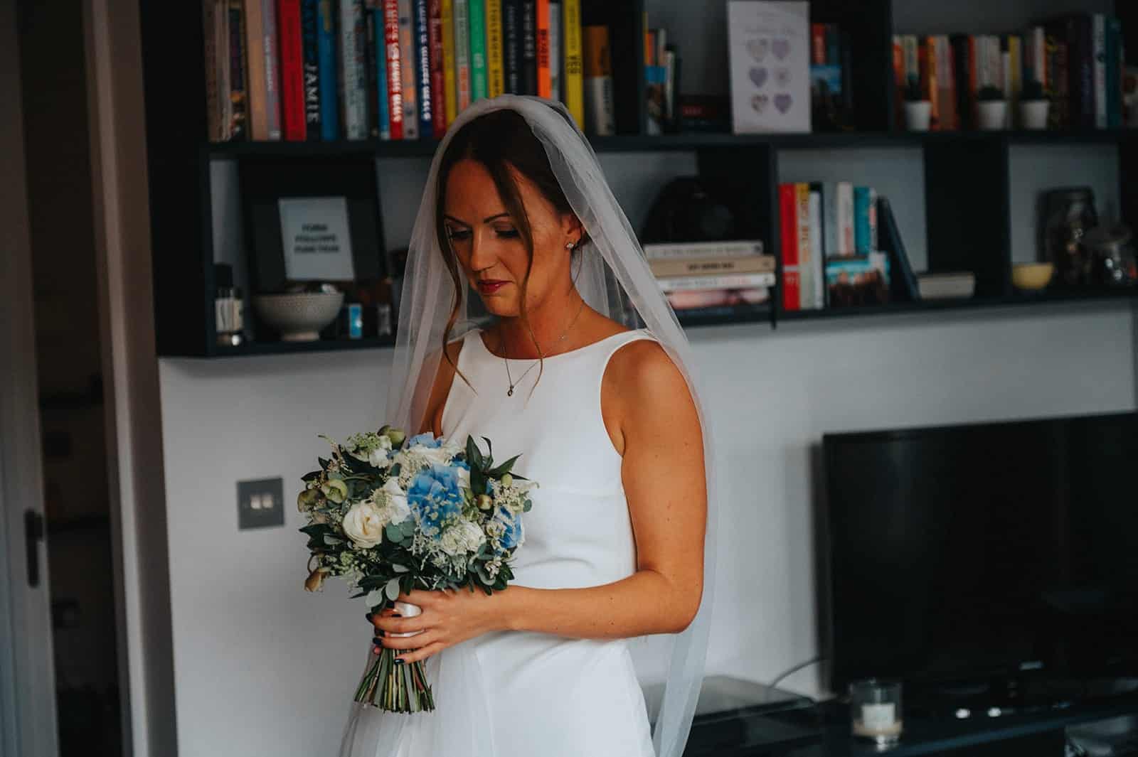 bride in dress with boat neckline holding bouquet 