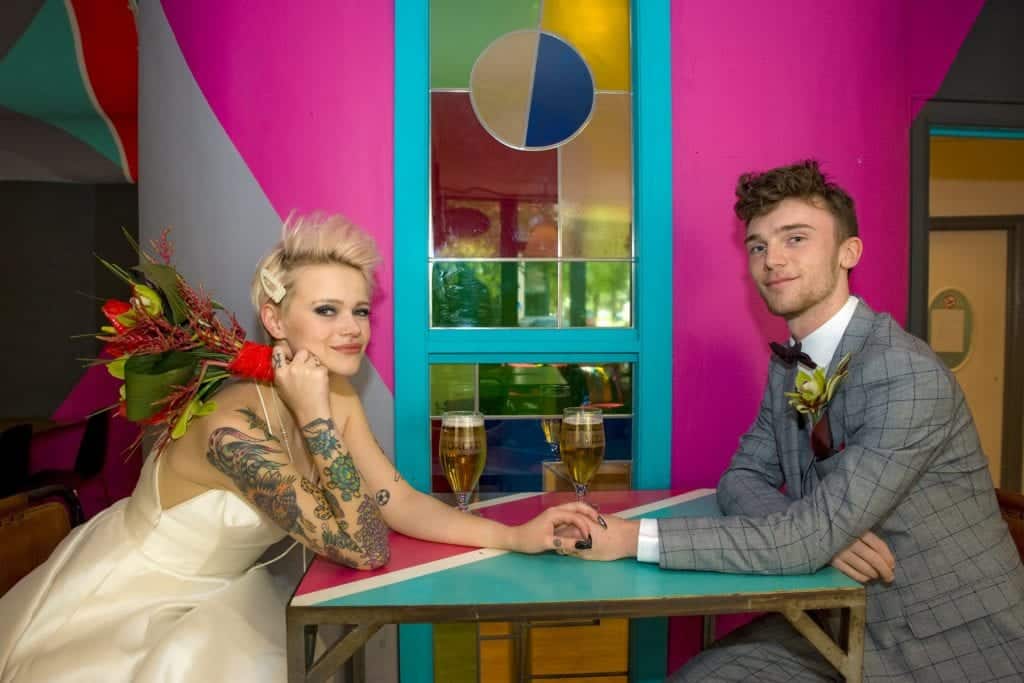 tattooed bride and groom in a colourful venue