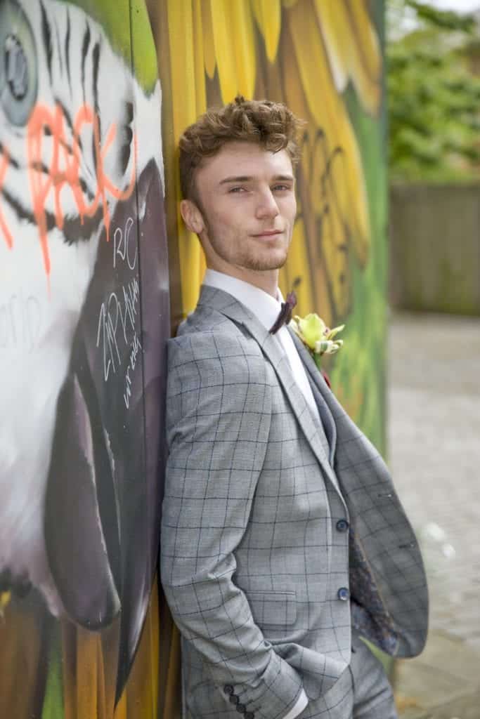 groom leaning on the colourful wall