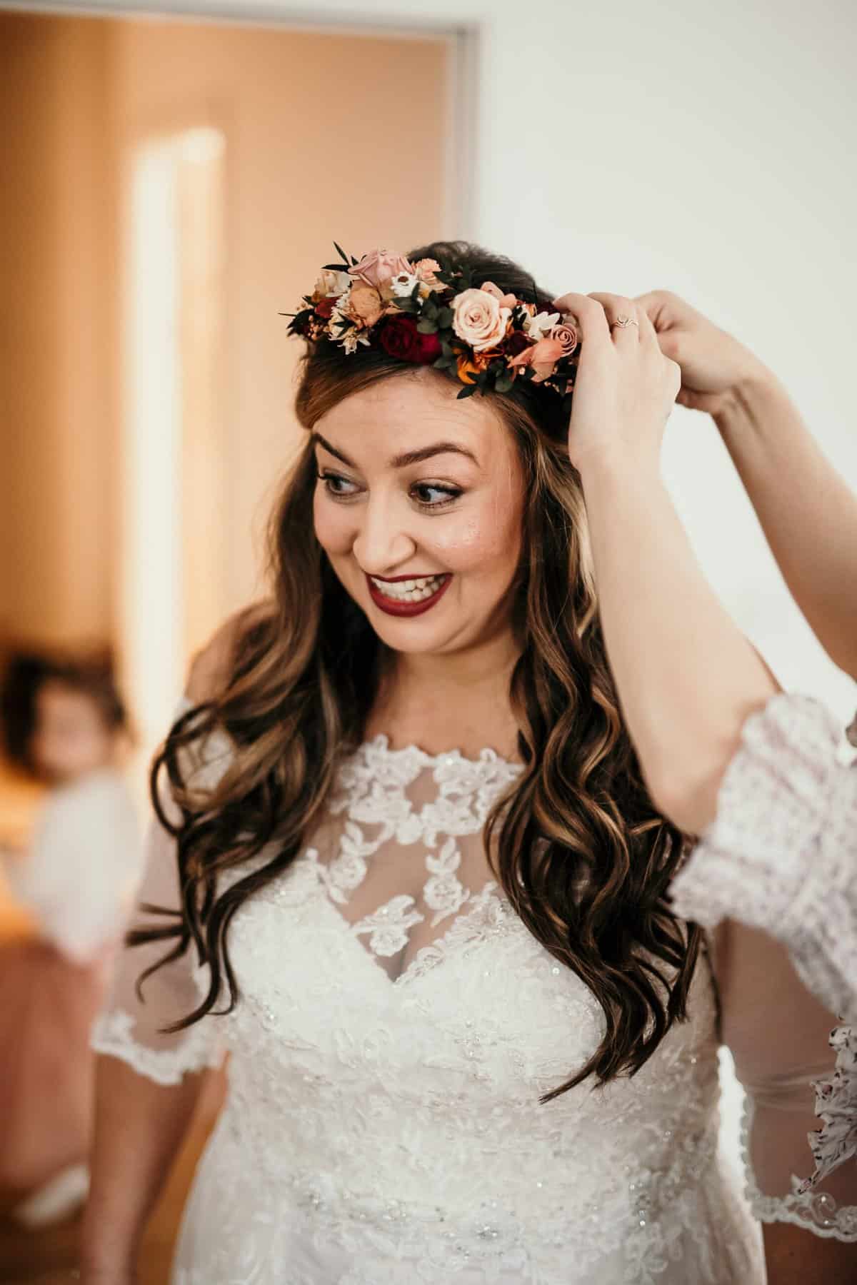 bride having her flower crown fitted WITH OFF THE SHOULDER WEDDNG DRESS.