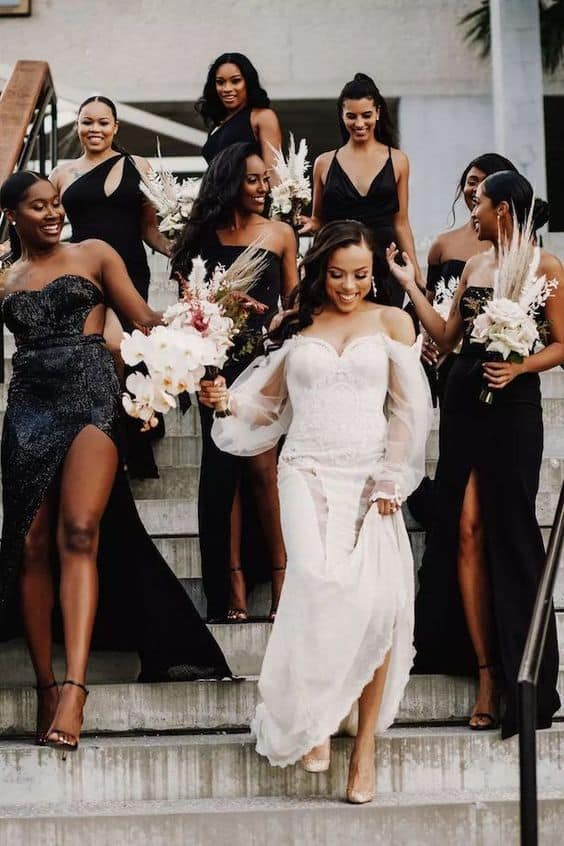 a bride and her bridesmaid wearing black dresses walking down steps heading to the ceremony