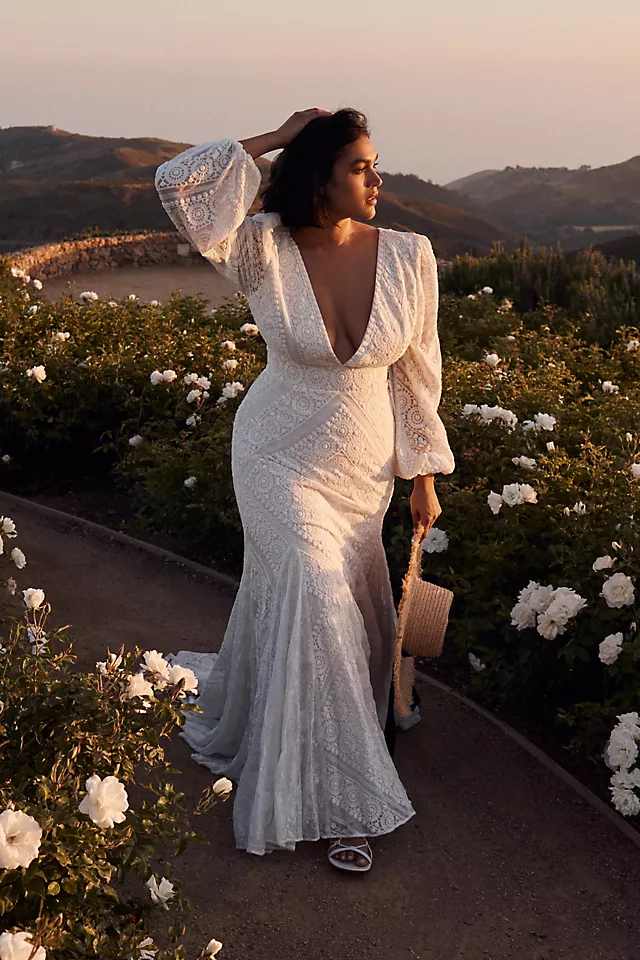 plus size model in a long sleeve lace wedding dress with low cut v neckline