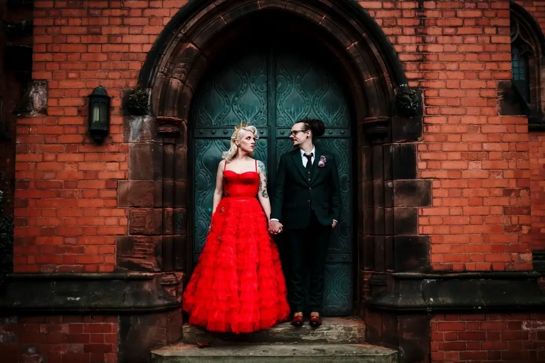 bride and groom posing on door way - bride in red and groom in black