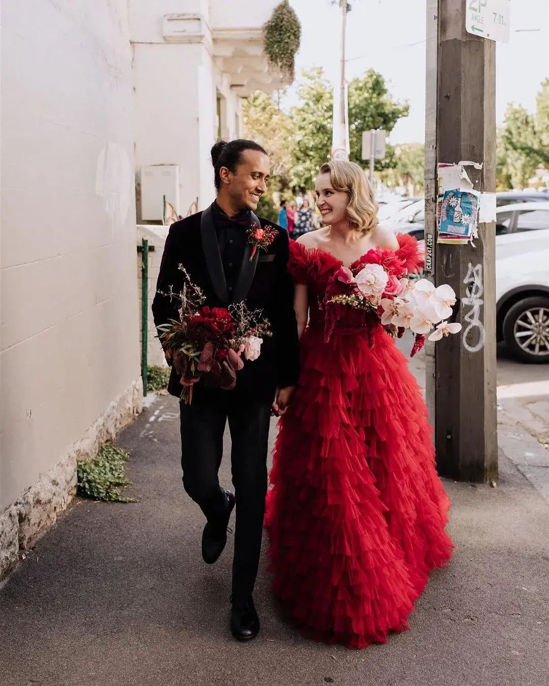 bride and groom walking down the street - bride in red dress with pink bouquet