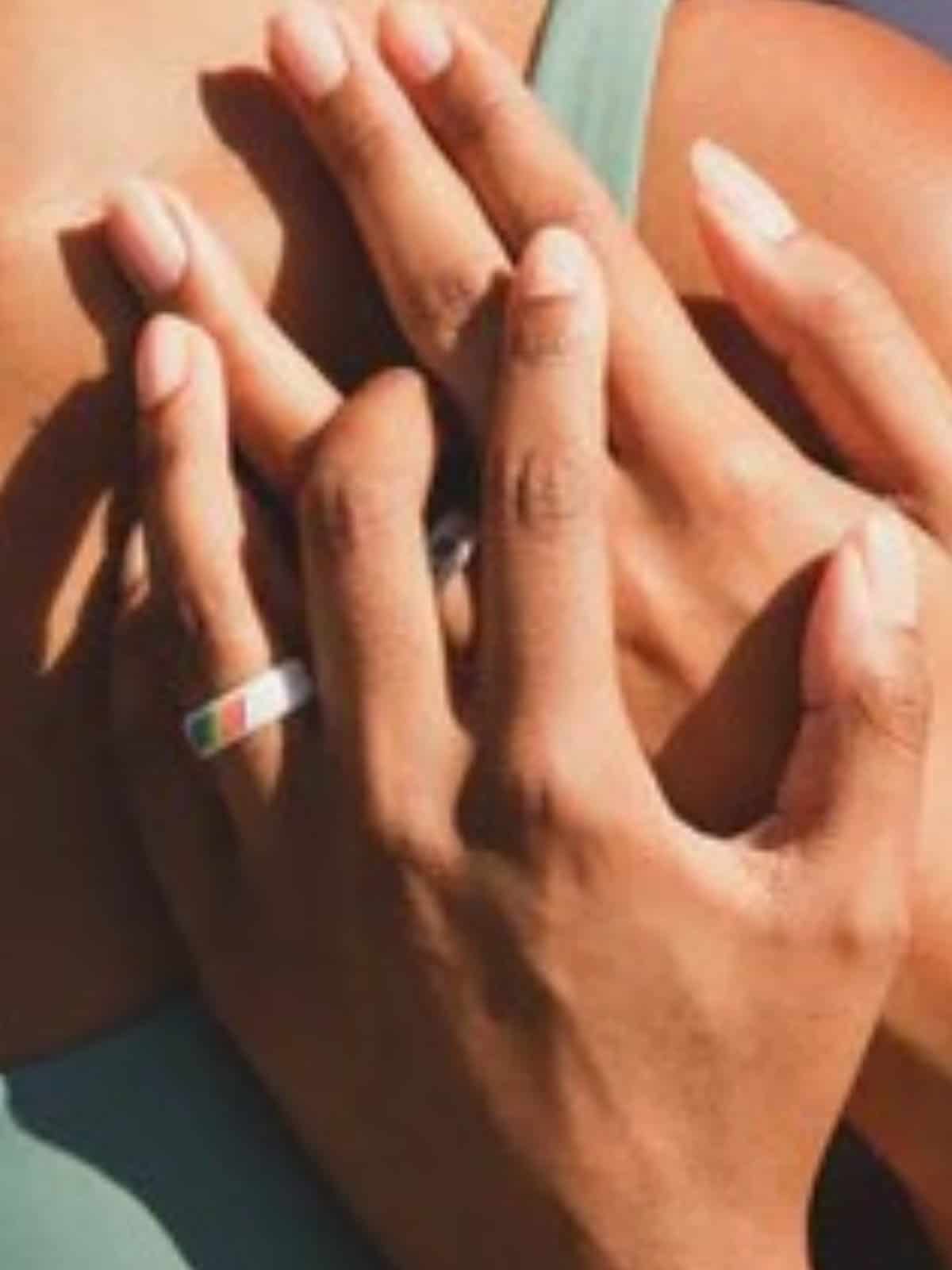 hand with white ring on finger with rainbow pride flag