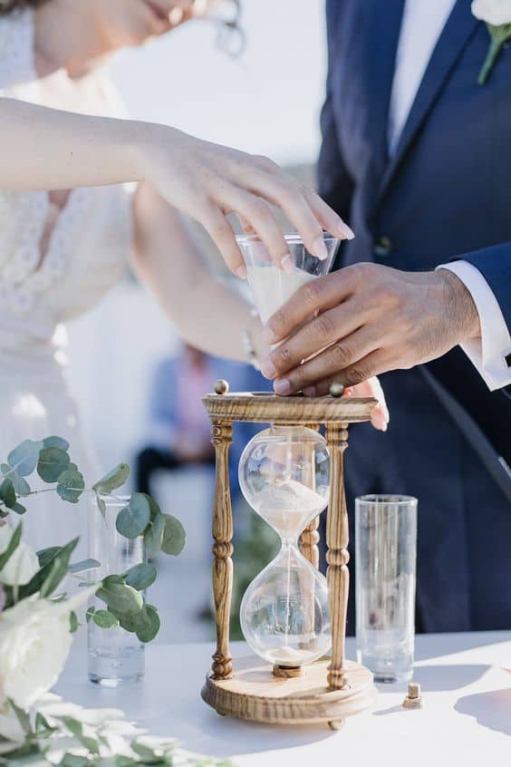 close up of a sand ceremony jar and 2 hands