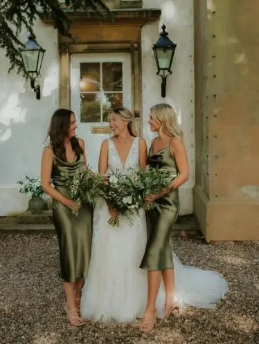 bride and 2 bridesmaid outside house holding bouquets 