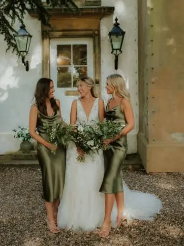 bride and 2 bridesmaid outside house holding bouquets