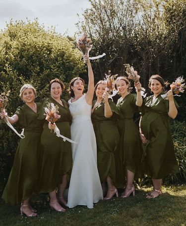 bride and bridesmaid cheering with flowers in the air 