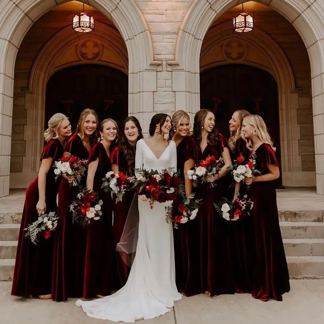 bride and bridesmaid on steps wearing red velvet dresses