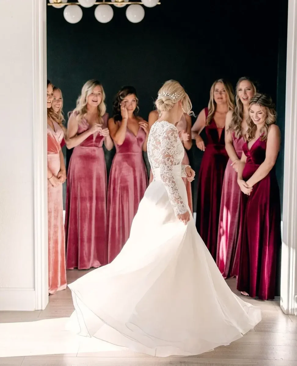 bride and bridesmaid first look - bridesmaids in pink velvet dresses