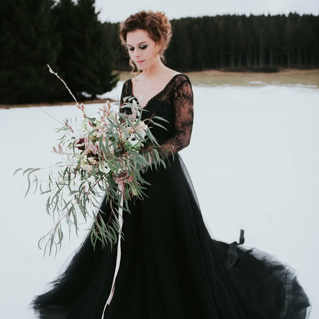 bride in snow with long lace sleeves and wild green bouquet