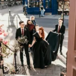 bride in black dress walking up steps with groom holding