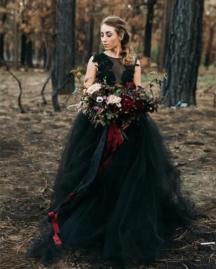bride in black wedding dress with bold red bouquet