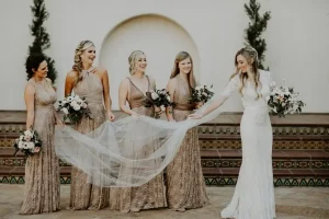 4 bridesmaid in multiway lace dresses holding brides veil