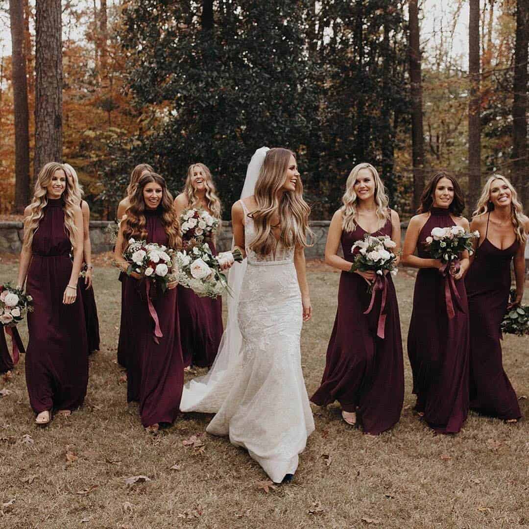 bride with bridesmaid in deep red different style bridesmaid dresses at an autumn wedding 