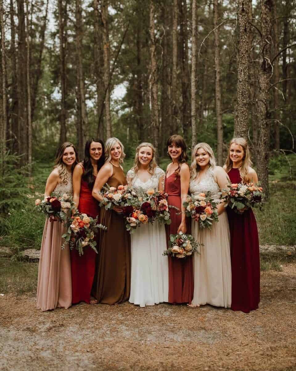 autumn wedding image - bride with bridesmaids in mismatched fall coloured dresses