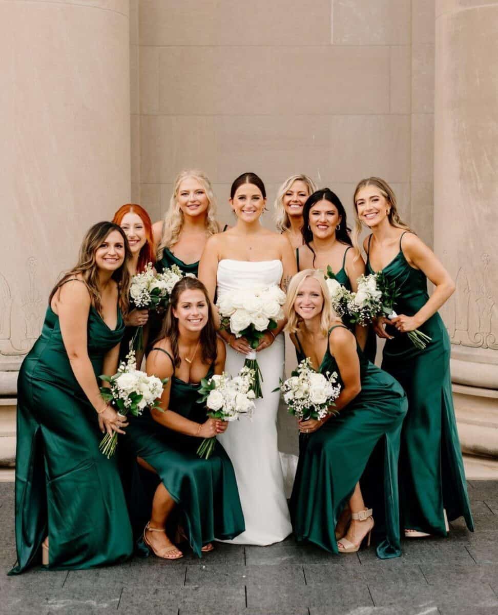 bride posing with bridesmaids in emerald green bridesmaid dresses 