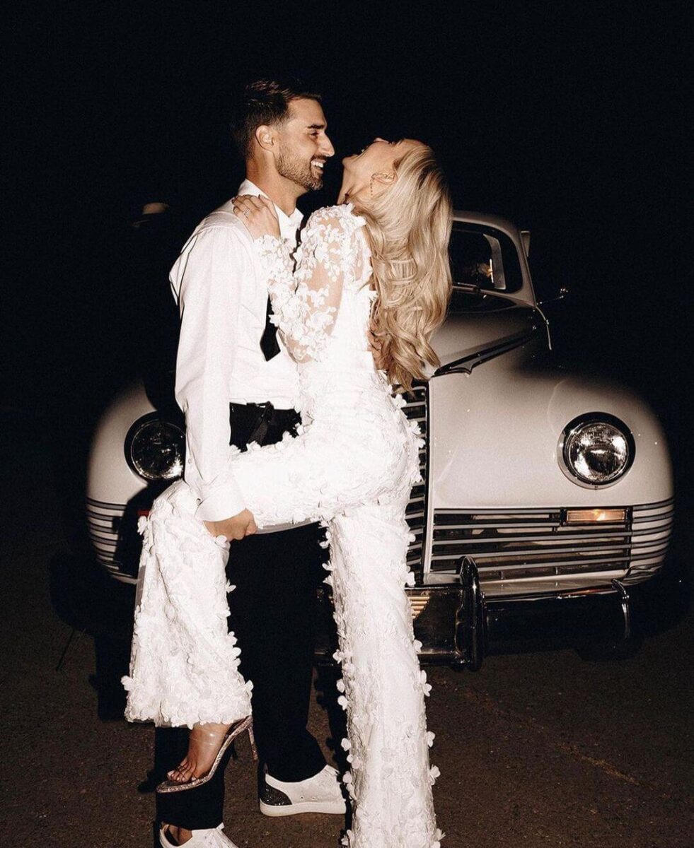 bride and groom in front of car, bride in a textured jumpsuit