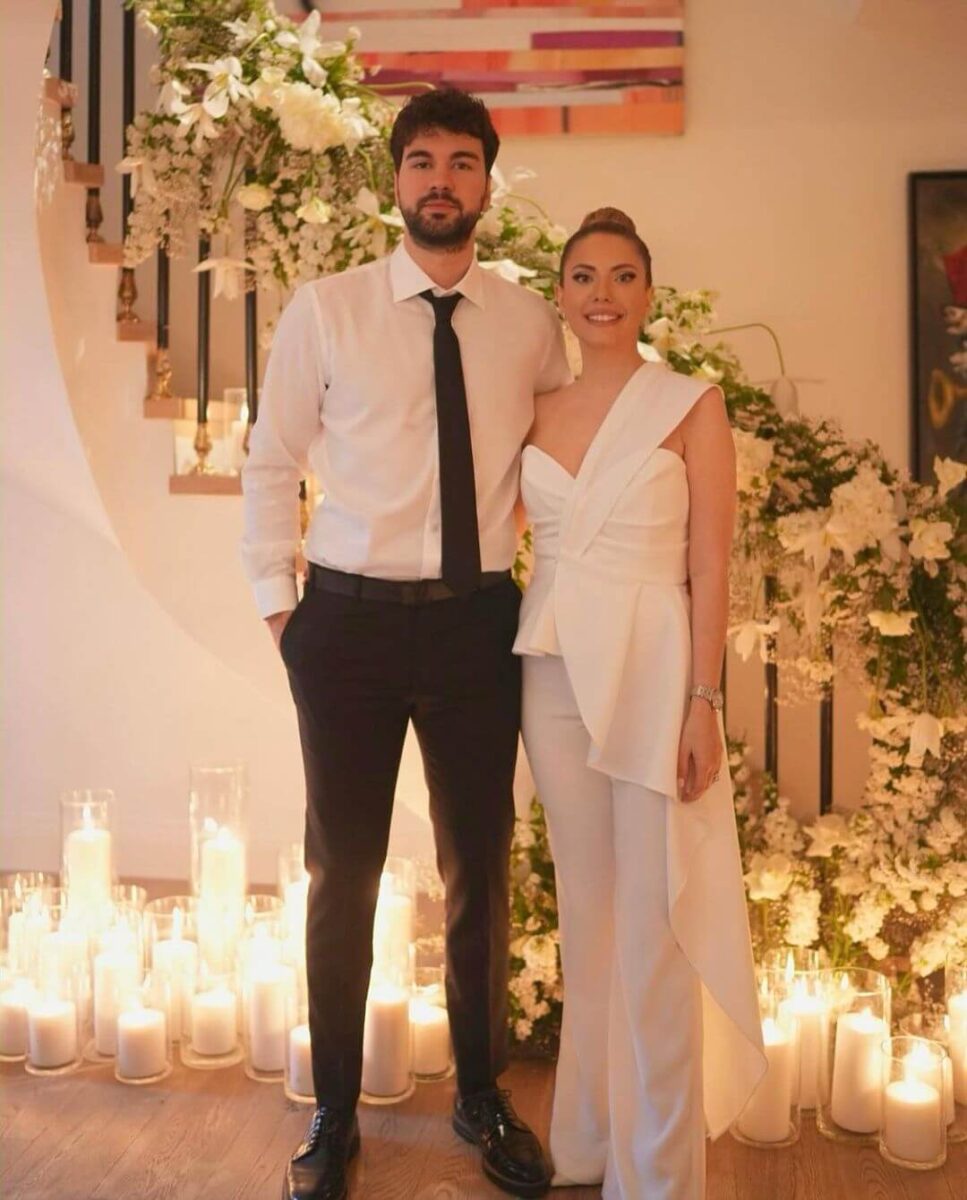 couple stood in front on stairs covered in candles, bride in one shoulder jumpsuit 