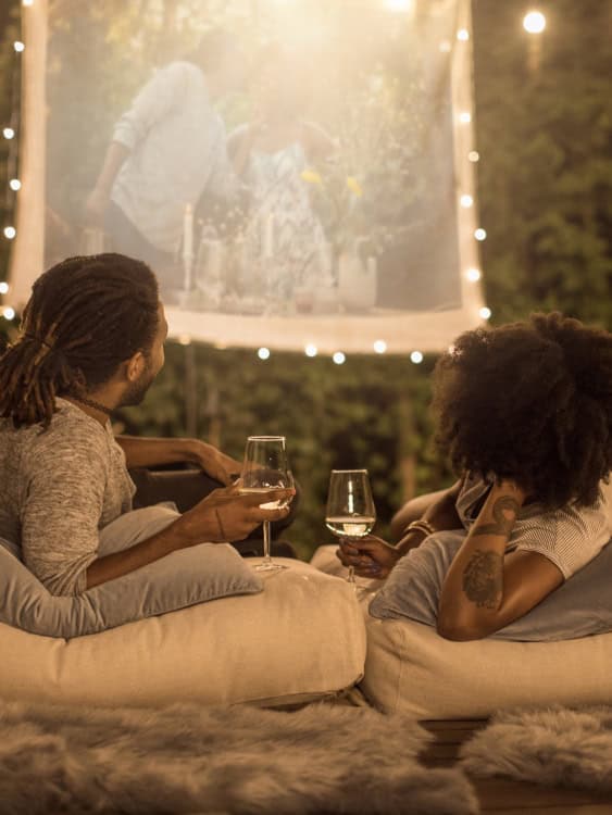 couple lay on cushions outside watching a movie