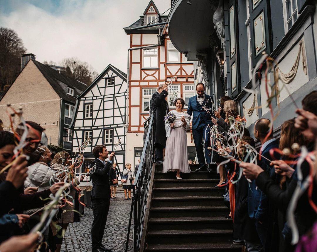 couple walking dow steps after wedding ceremony and guests waving wand bells