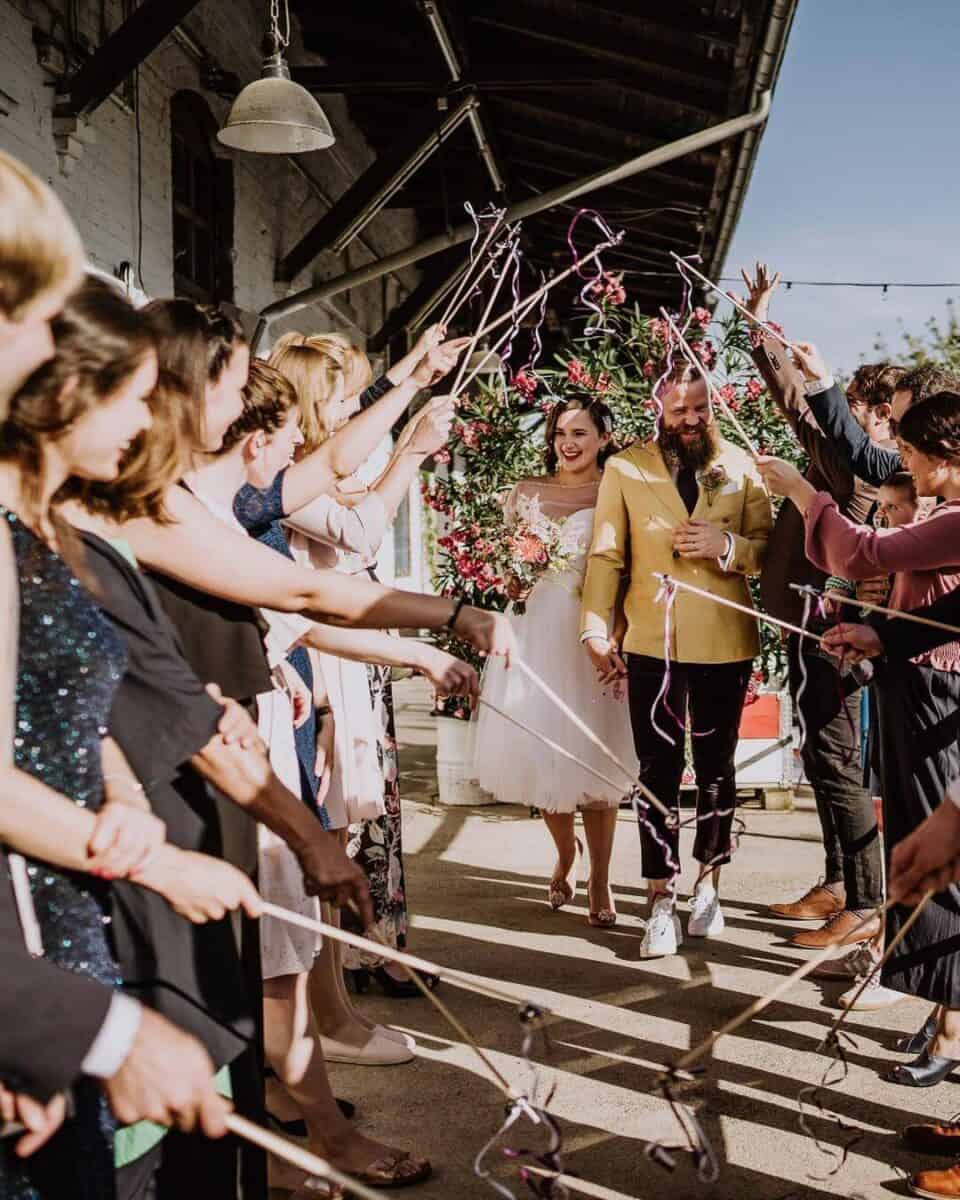 couple exiting wedding and guests waving wedding bell wands