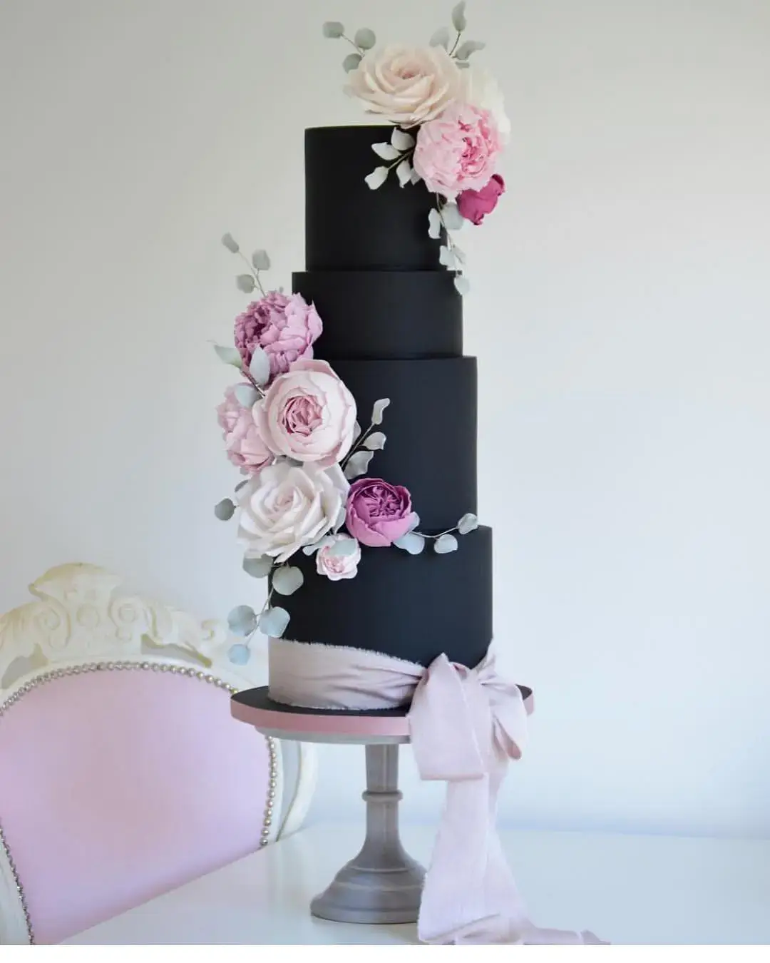 black wedding cake with pretty icing flowers and chiffon bow