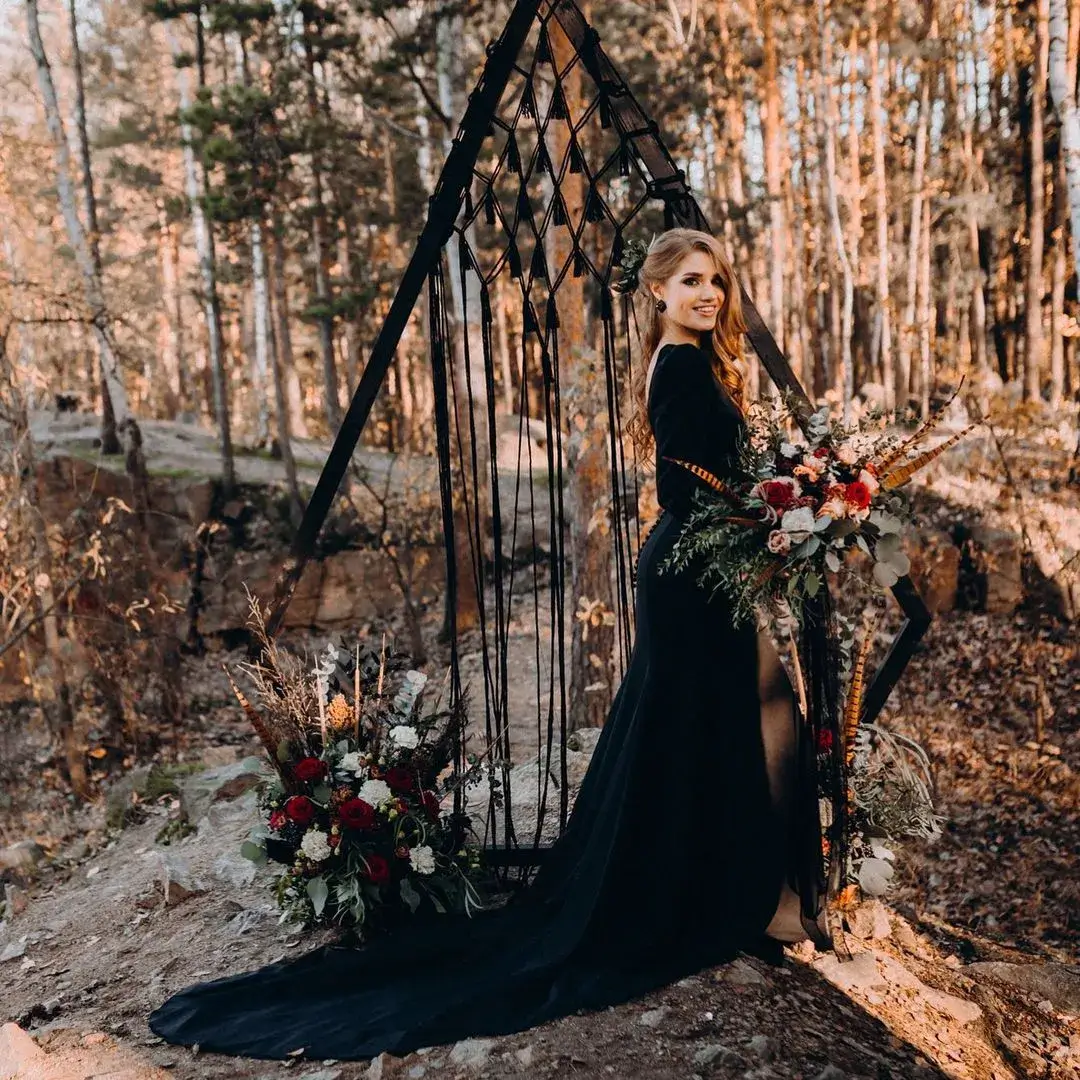 bride in black lace dress in front of ceremony arch