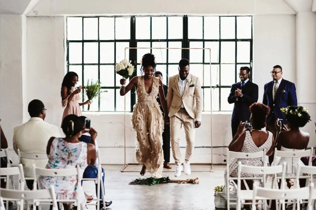 couple jumping the broom in a warehouse wedding venue