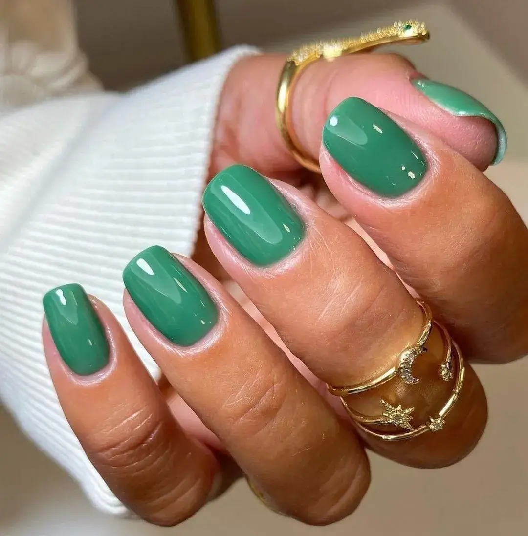 green nails on a mothers hand with gold rings
