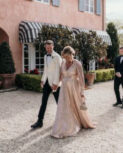 mother and father walking in front of wedding venues, mother in long gold sequin dress