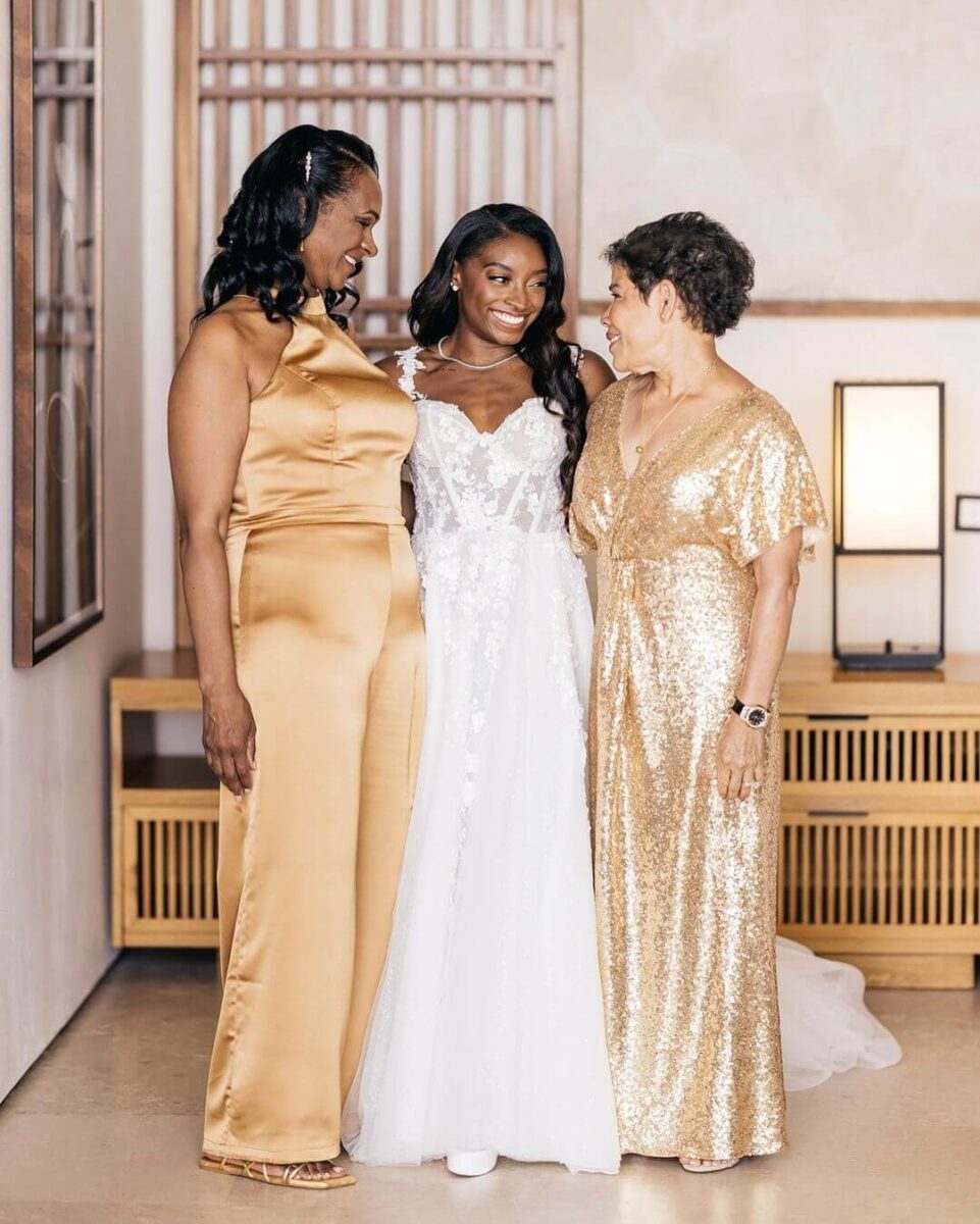 bride with mother of bride and groom, both in jumpsuits in gold, one sequin, one satin