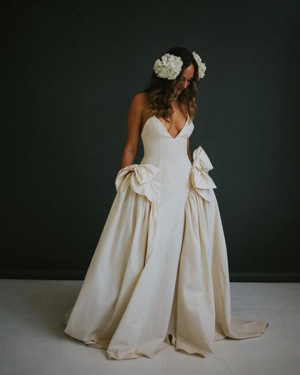 bride in simple dress with big bow added on hips to create fuller skirt