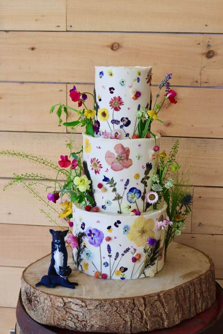 presses floral wedding cake with dog topper