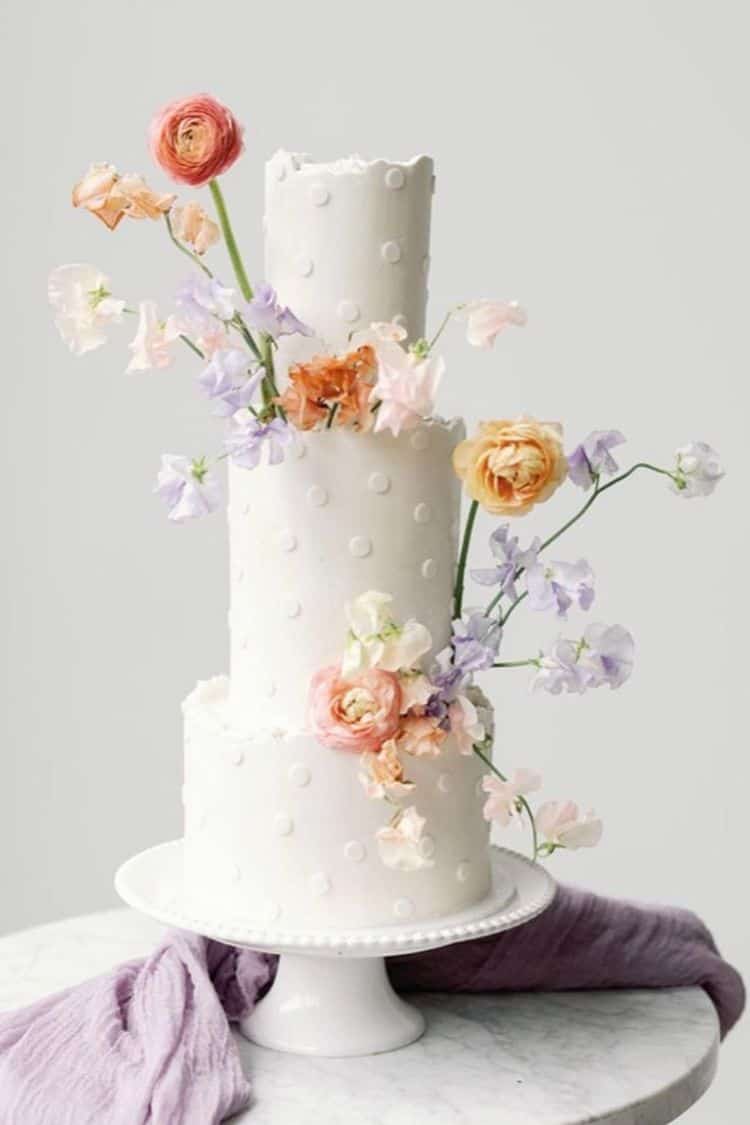 white cake with dots and  pastel flowers 