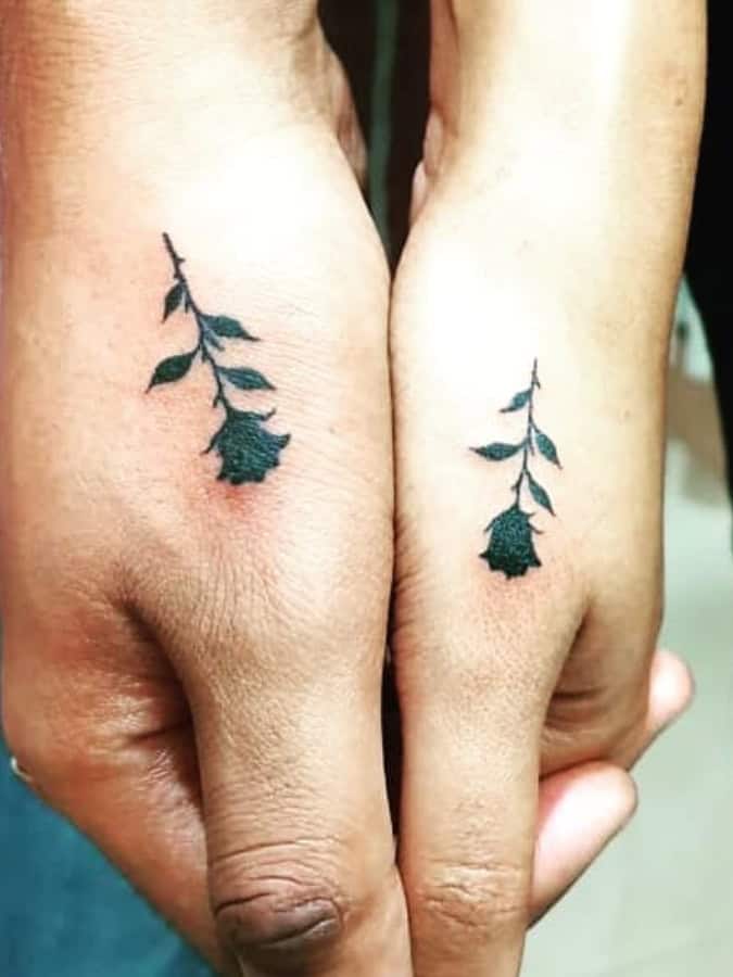 2 hands with matching black rose tattoos