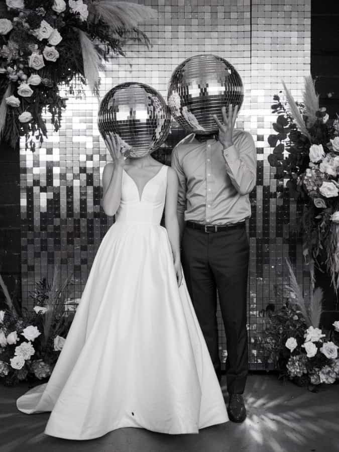 wedding couple holding large disco balls over face