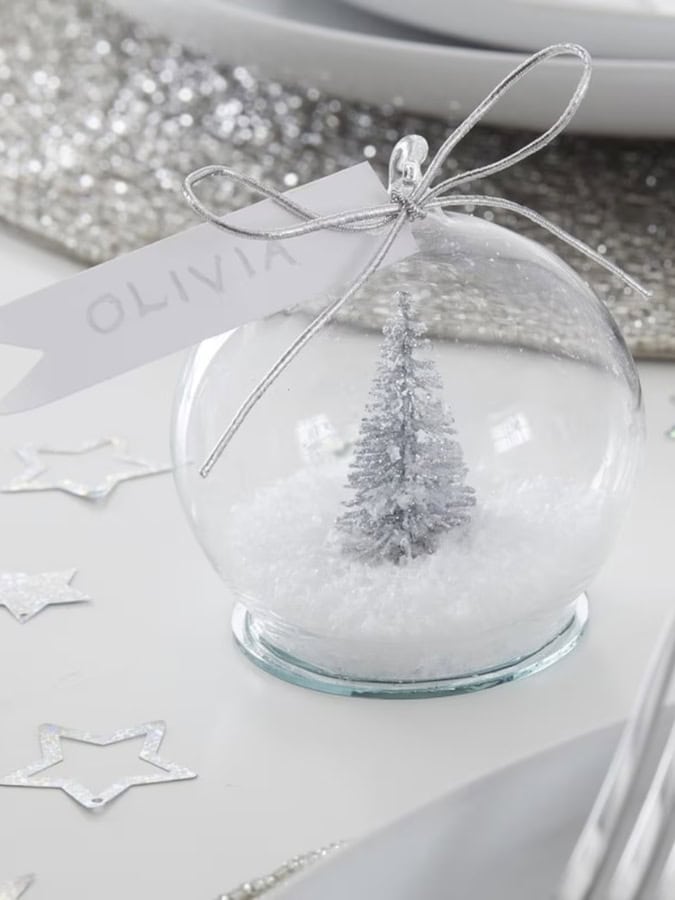 personalised snow globe wedding favor with tree and snow inside on table