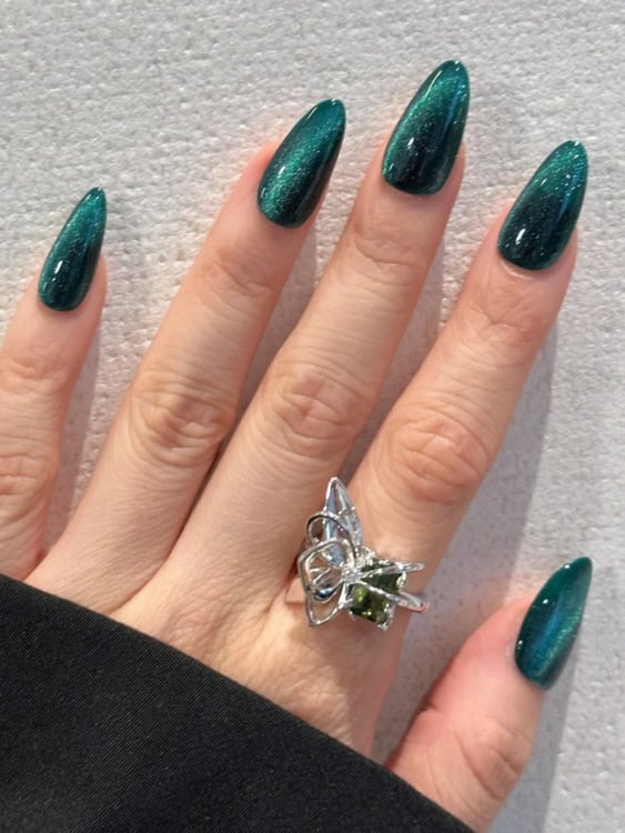 These long, almond-shaped nails feature a teal-green cat-eye polish that gives off a shimmery, reflective effect. 