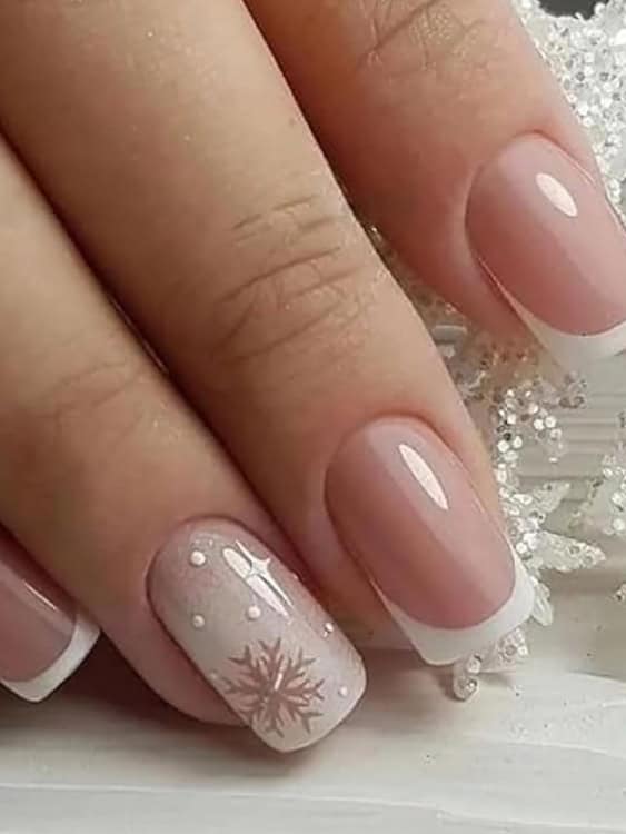 These nails feature a classic French tip style with a seasonal twist: a delicate snowflake and tiny snow-like dots on the accent nail. 