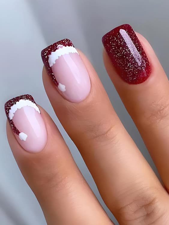 The red glitter French tips are shaped to mimic the curve of a Santa hat, complete with fluffy white detailing along the base and a little pom-pom at the tip. 