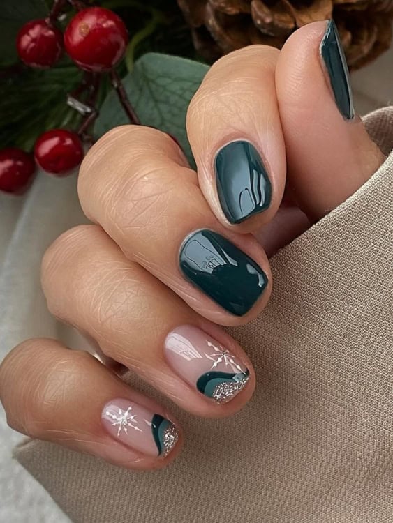 These nails have a rich, deep green polish that’s paired with a minimalist snowflake accent on a nude base, along with a bit of silver glitter for a touch of sparkle. 