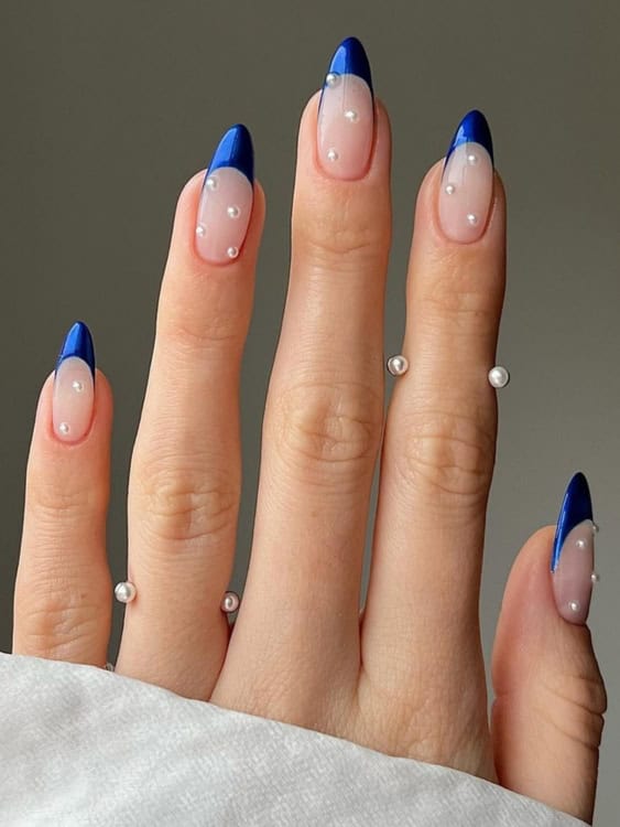 These nails combine a bold, royal blue French tip with small pearl embellishments scattered across the nail. 