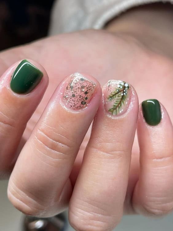  this design uses deep green polish paired with a glitter accent and delicate pine branch detailing. 