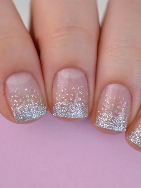 These nails have a clear base with a glittery silver gradient at the tips, creating a soft frosted look. 