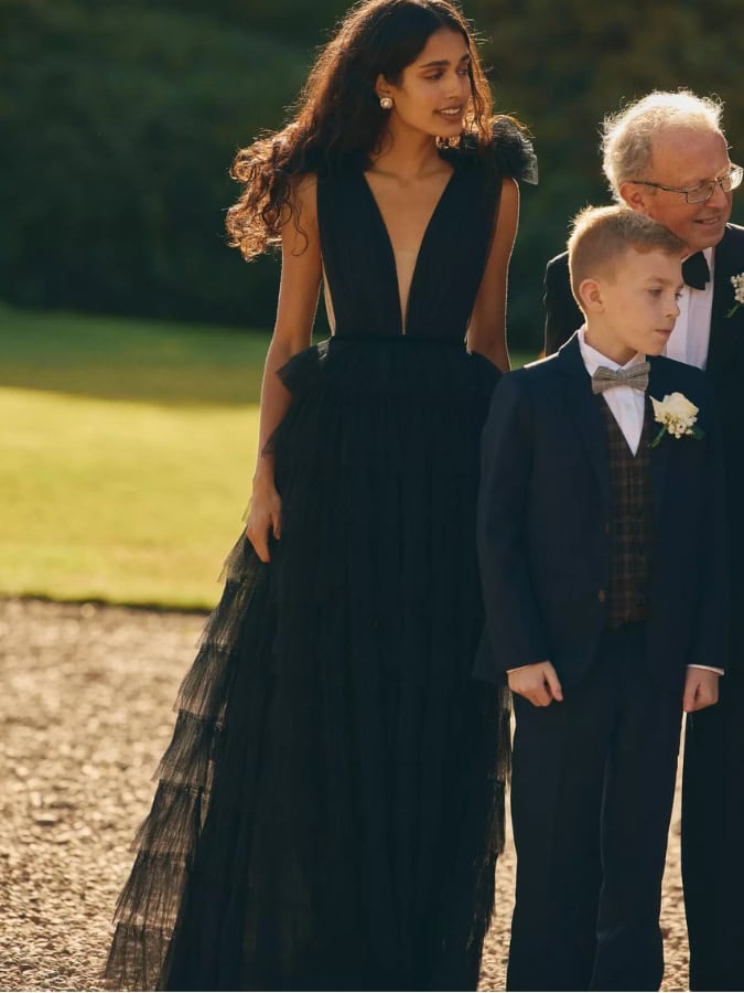 women in tulle black dress stood with 2 children in suits at a winter wedding