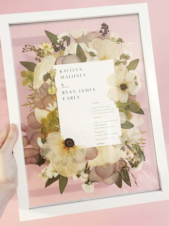 framed pressed flowers surrounding wedding invite