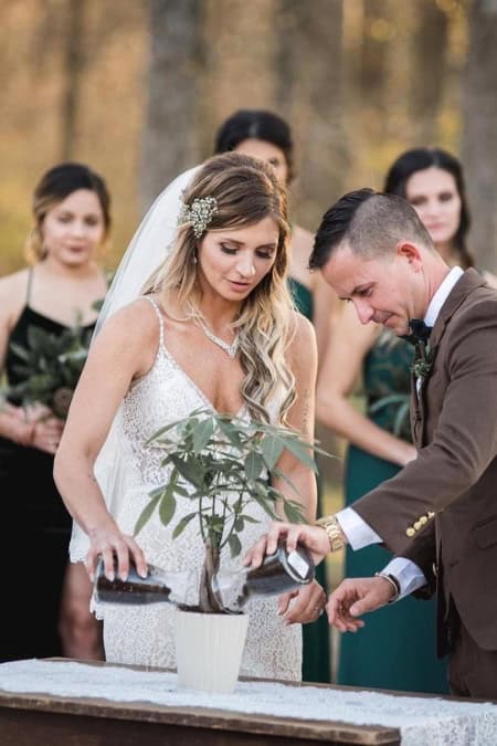 couple pouring their jars of dirt into the pot of a tree at their unity wedding ceremony 