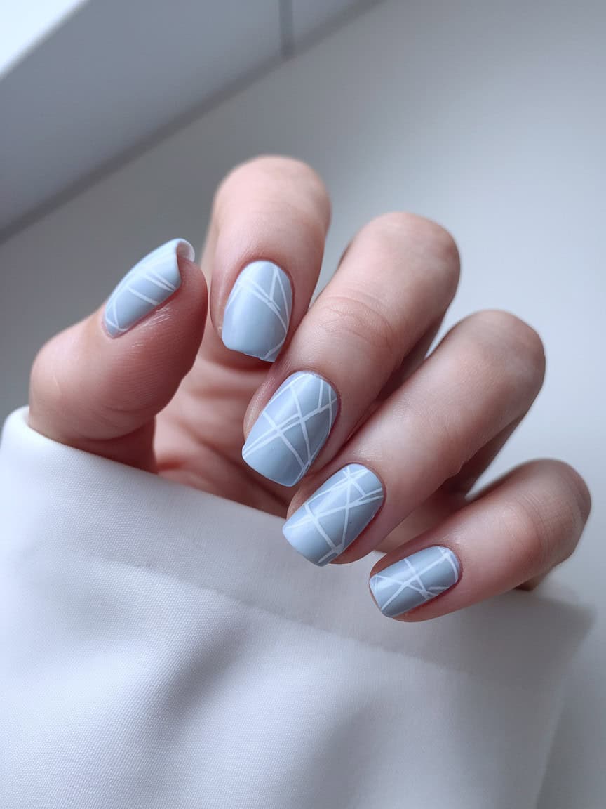 Light blue nails with white geometric patterns.